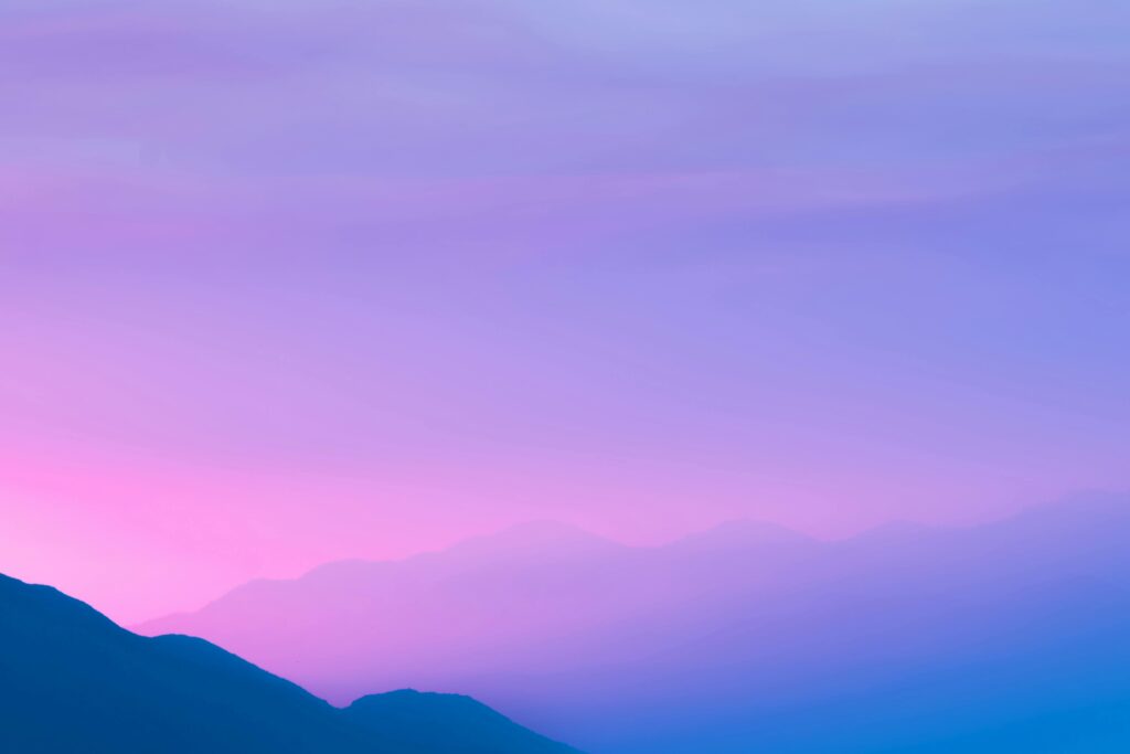 A beautiful silhouette of mountains against a gradient sky in purple and pink shades.